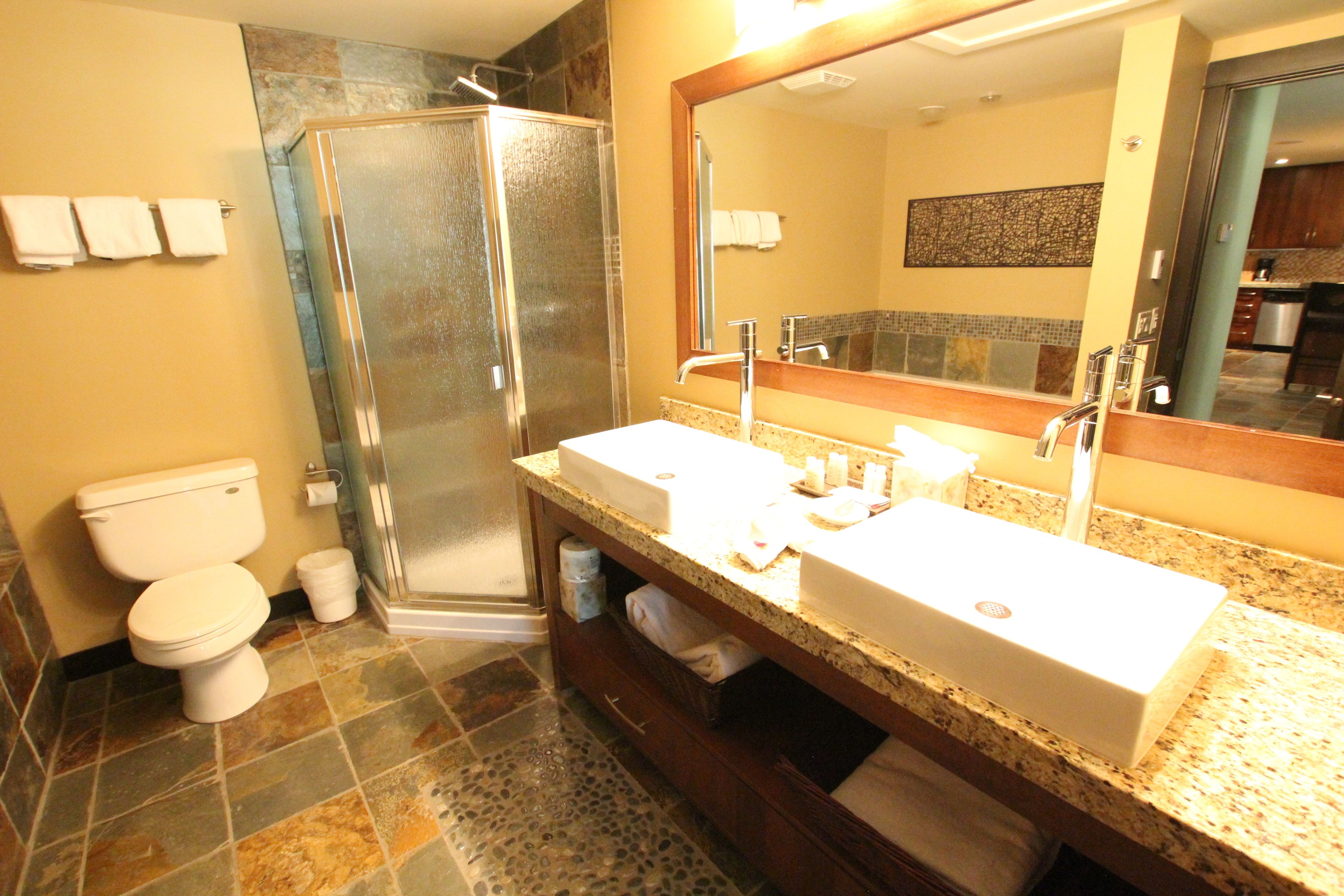 A bathroom with a glass-enclosed shower, a white sink, and a large mirror.