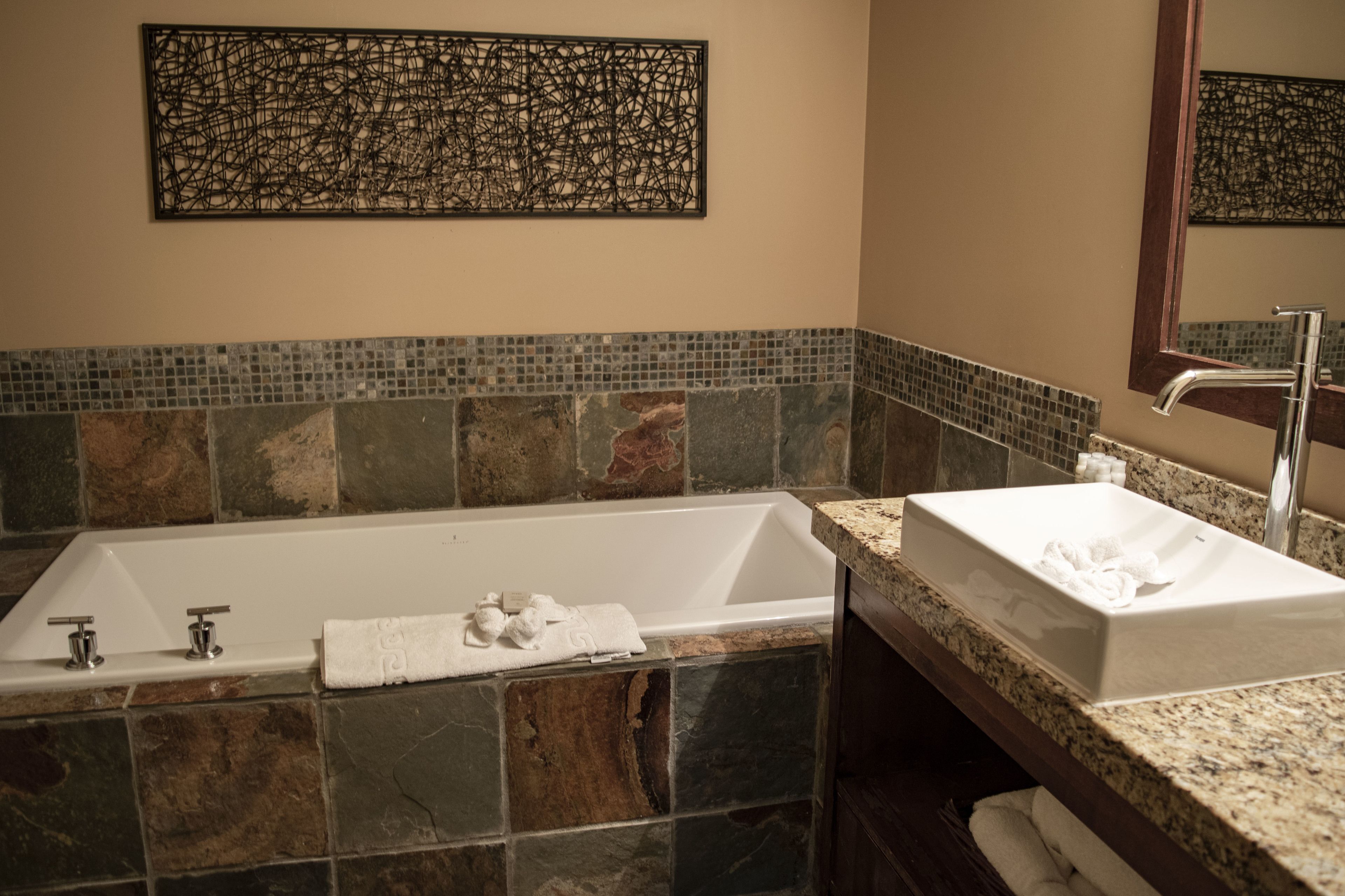 Un baño con una bañera grande, un lavabo y un espejo.