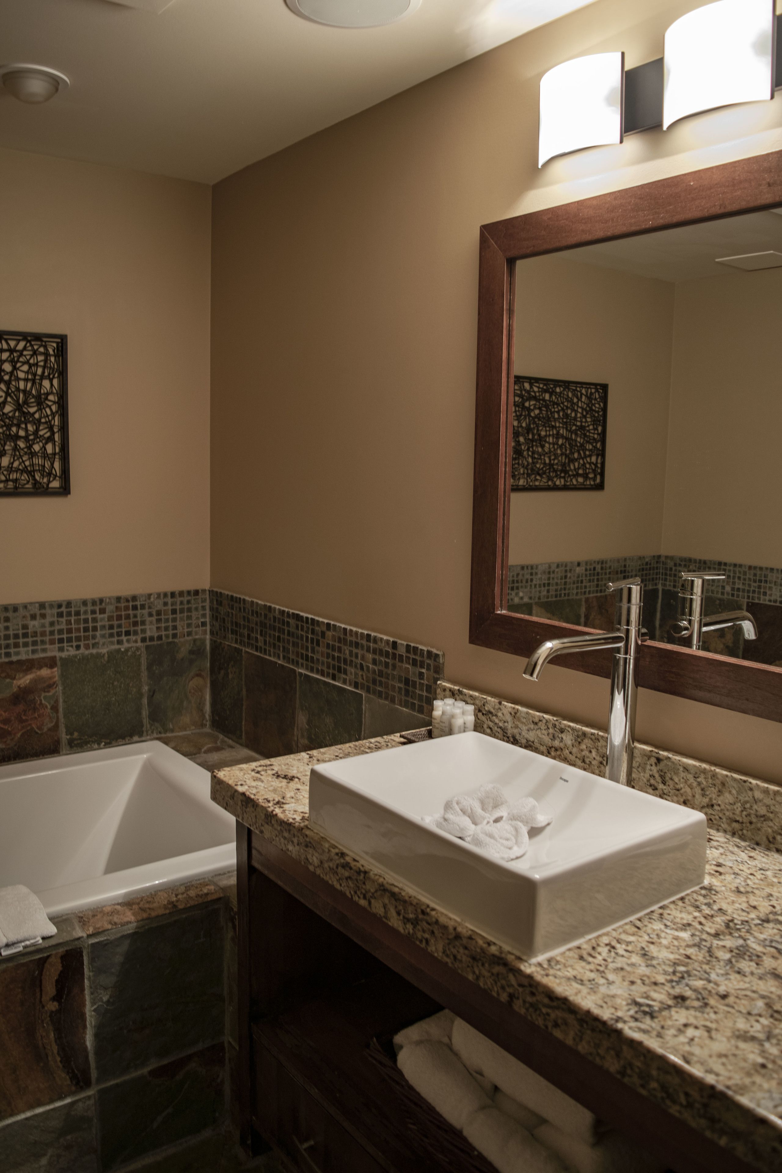 A bathroom with a white sink, a large mirror, and a bathtub.