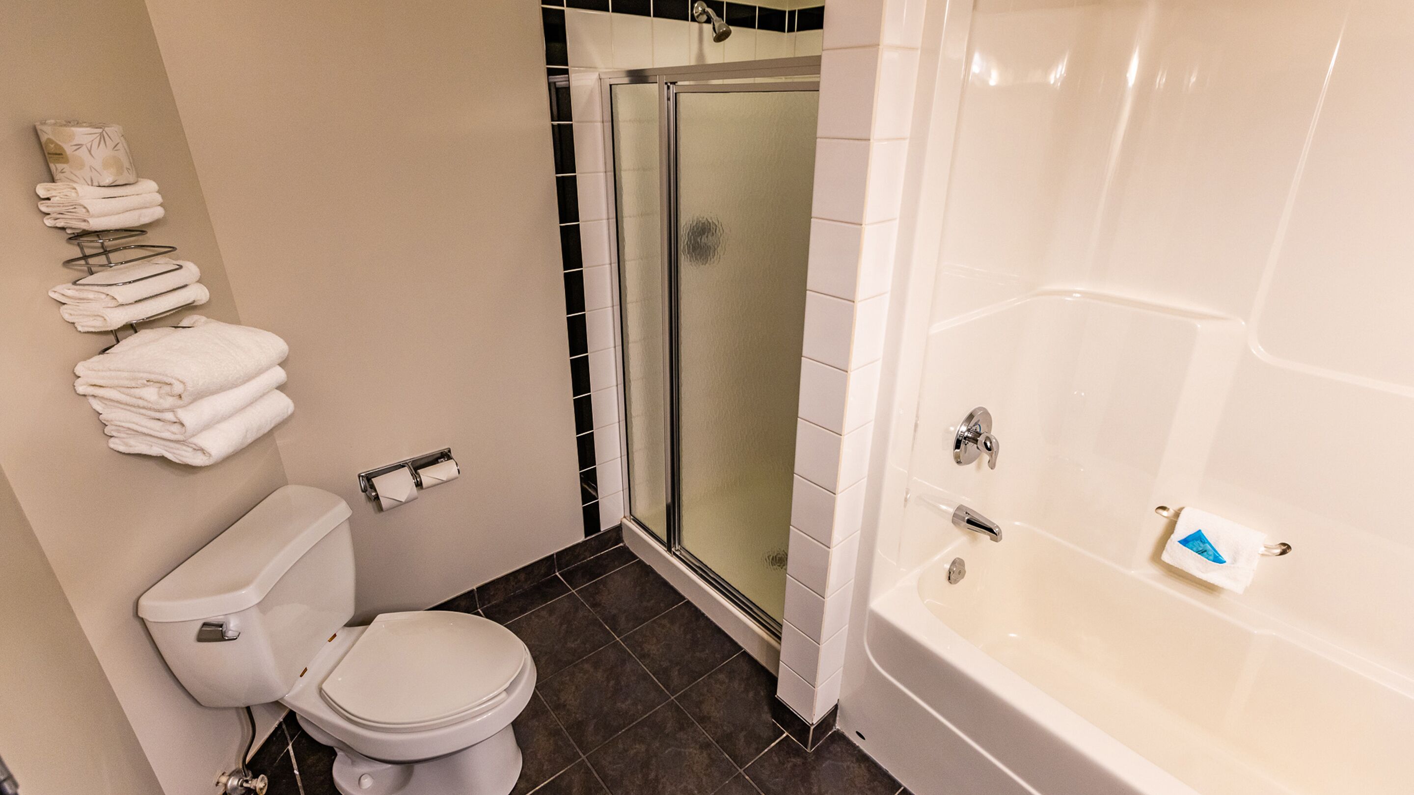 Un baño con inodoro, ducha con cerramiento de vidrio y bañera.