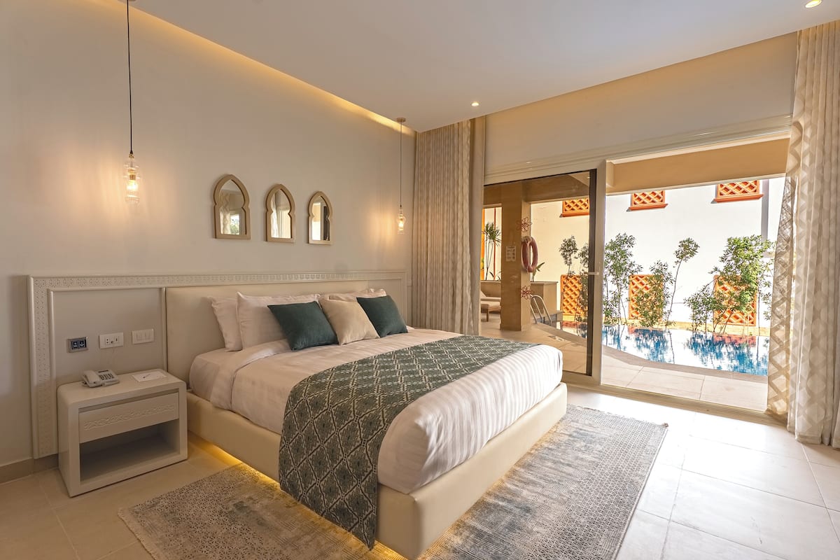 Un dormitorio moderno con una cama grande, mesitas de noche y vistas a una piscina y zona exterior.