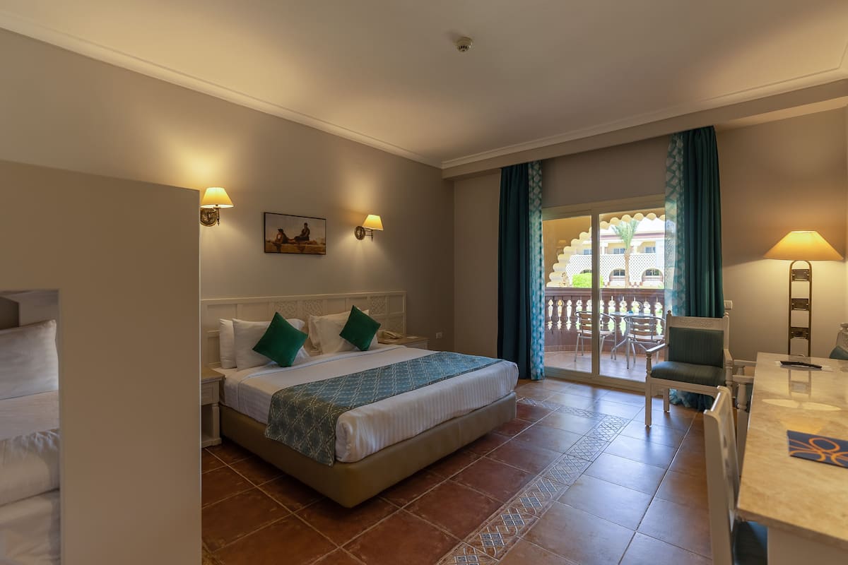 Habitación de hotel con cama, escritorio y balcón con vistas.