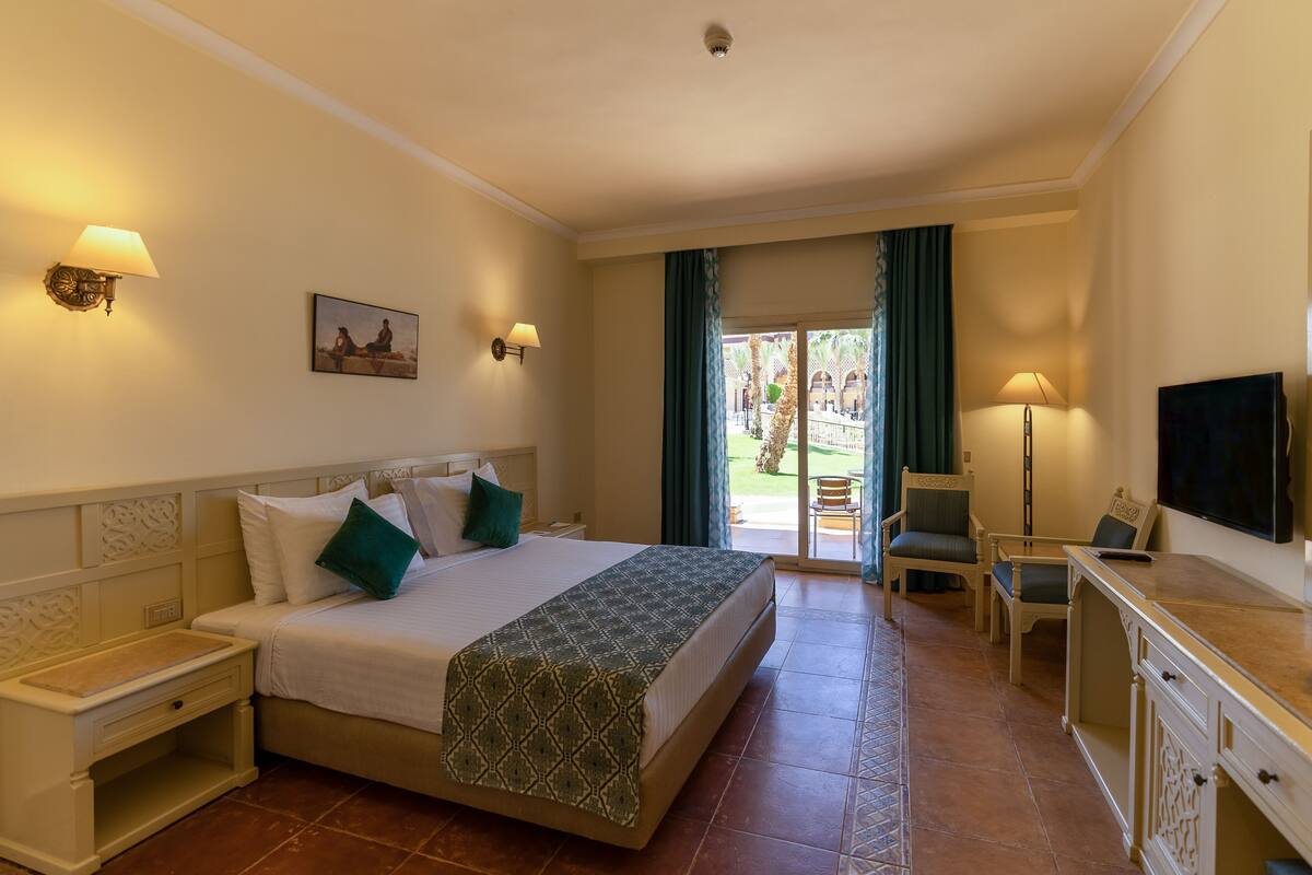 Una habitación de hotel con cama, mesitas de noche, escritorio, silla y televisión.