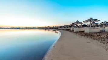 Een privéstrand, ligstoelen aan het strand, parasols, strandlakens