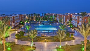 Ein Resort mit einem zentralen Pool, Palmen und Meerblick.