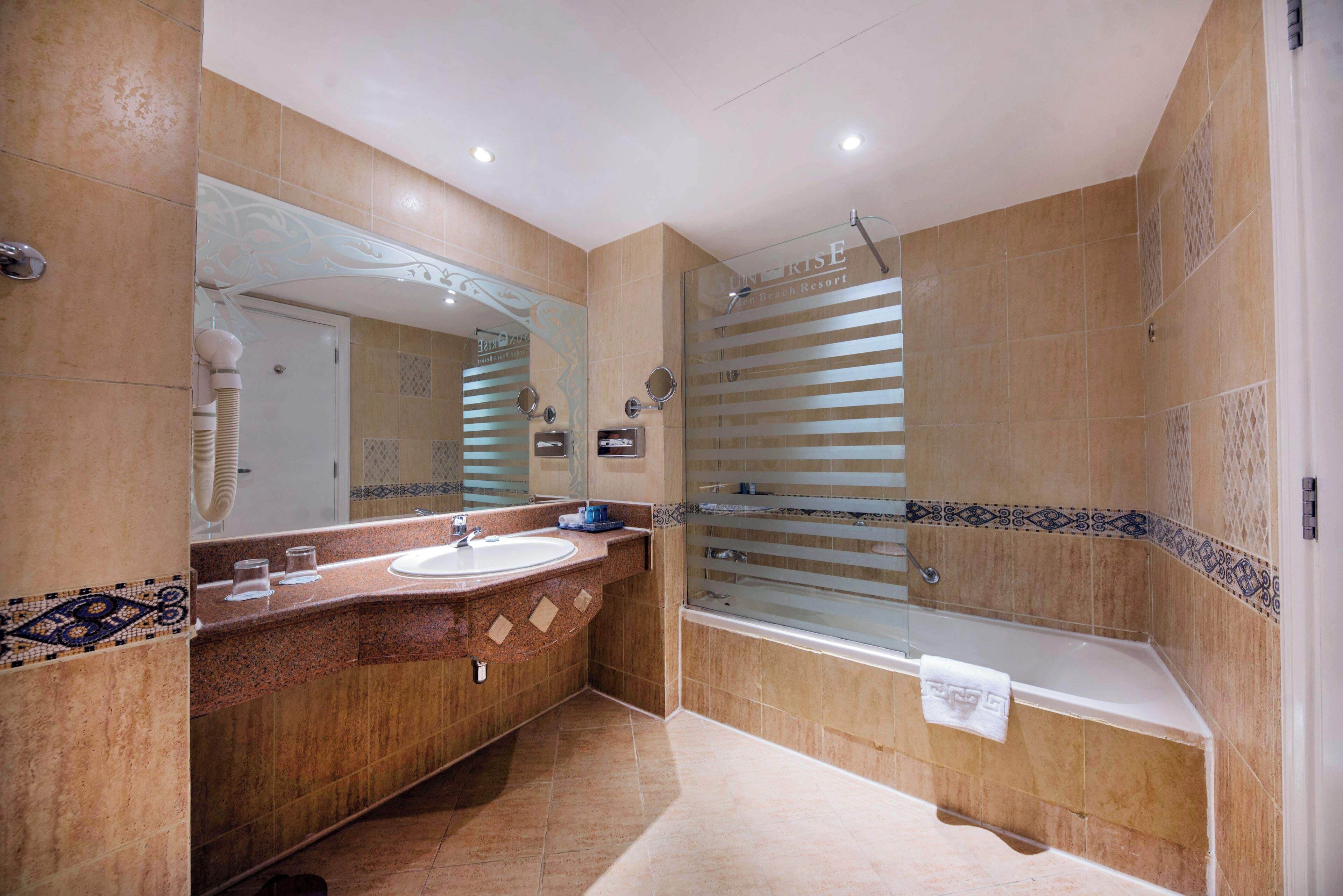A modern bathroom with a large mirror, two sinks, a bathtub, and a shower.