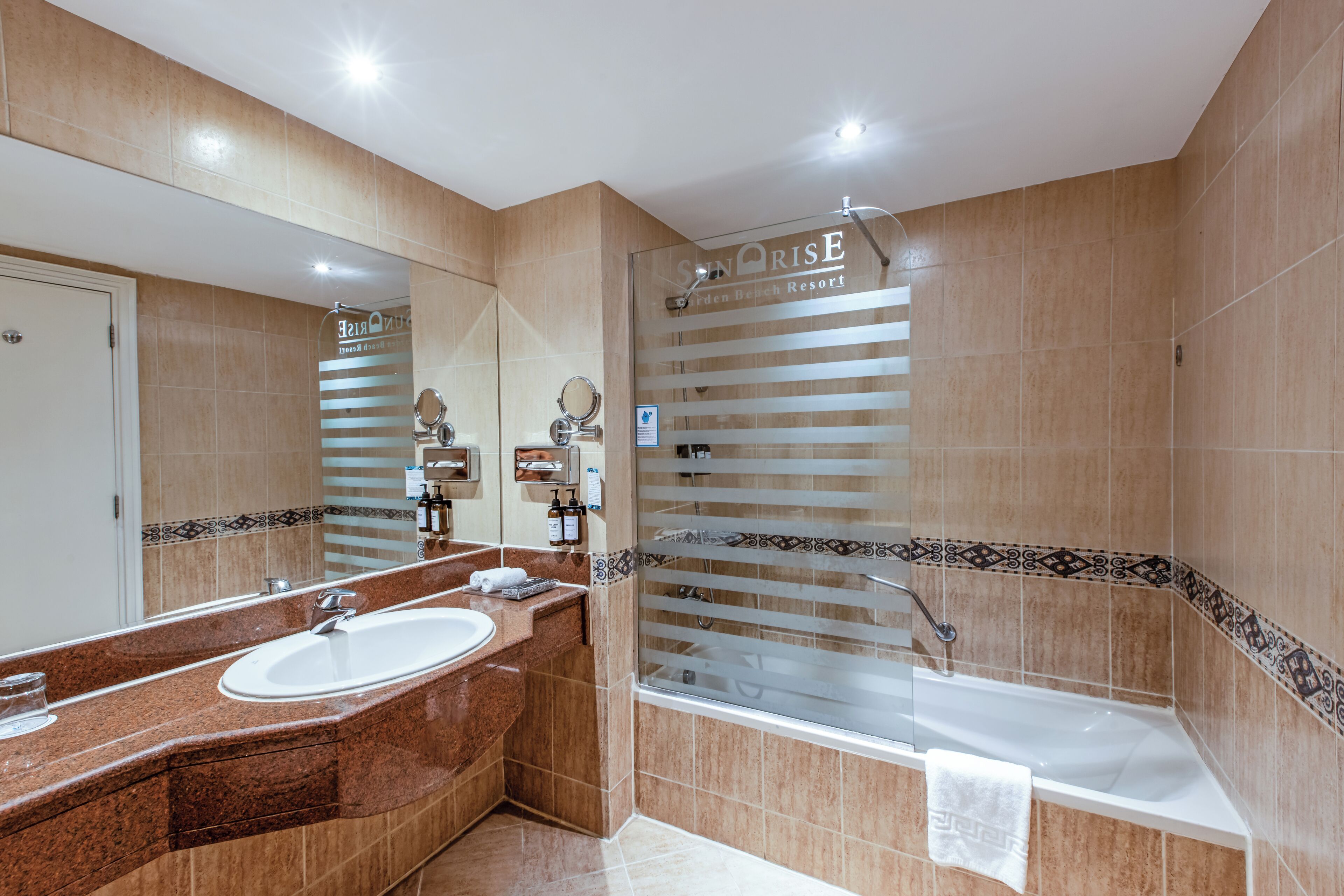 A modern bathroom with a large mirror, a sink, and a bathtub.