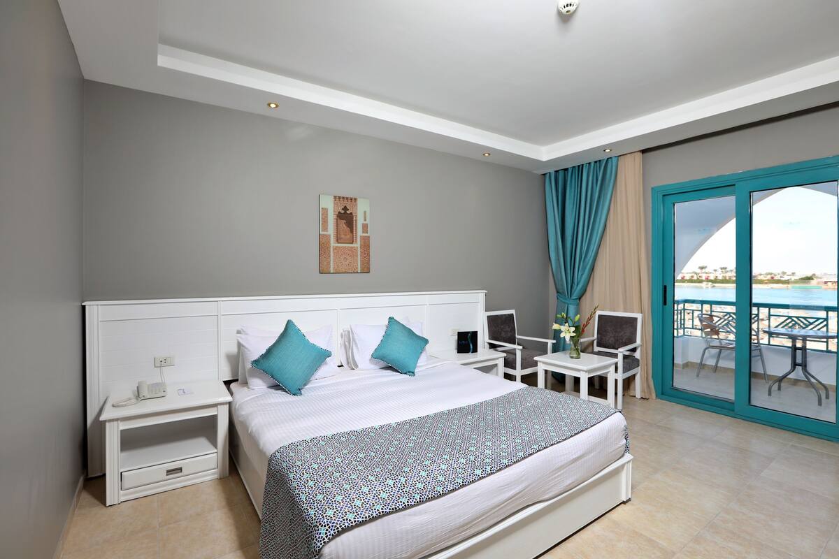 Una habitación de hotel con cama, mesitas de noche, escritorio y vistas al exterior.