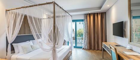 A hotel room with a four-poster bed, a desk with a chair, a flat-screen TV, and a large window with curtains.