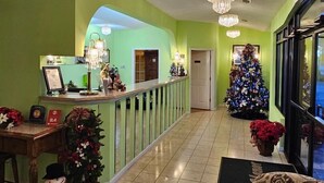 A lobby with a reception desk, a Christmas tree, and chandeliers.