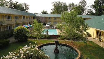 A hotel with a swimming pool, a fountain, and a covered outdoor area with umbrellas.