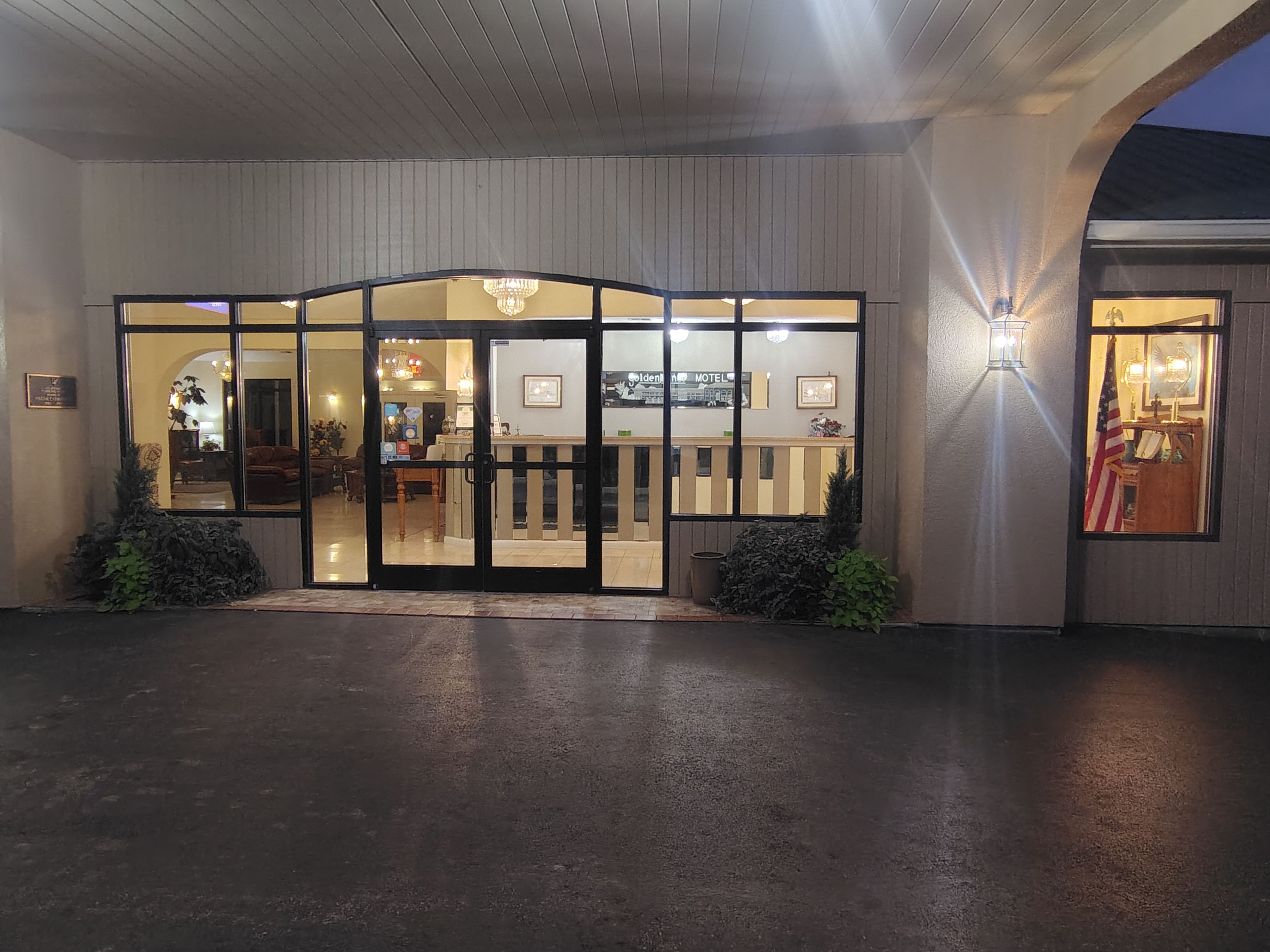 L’entrée d’un hôtel, avec un comptoir d’accueil, un lustre et une vue sur le hall.