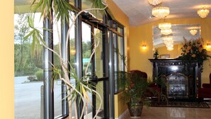 A room with large windows, a fireplace, and multiple chandeliers.