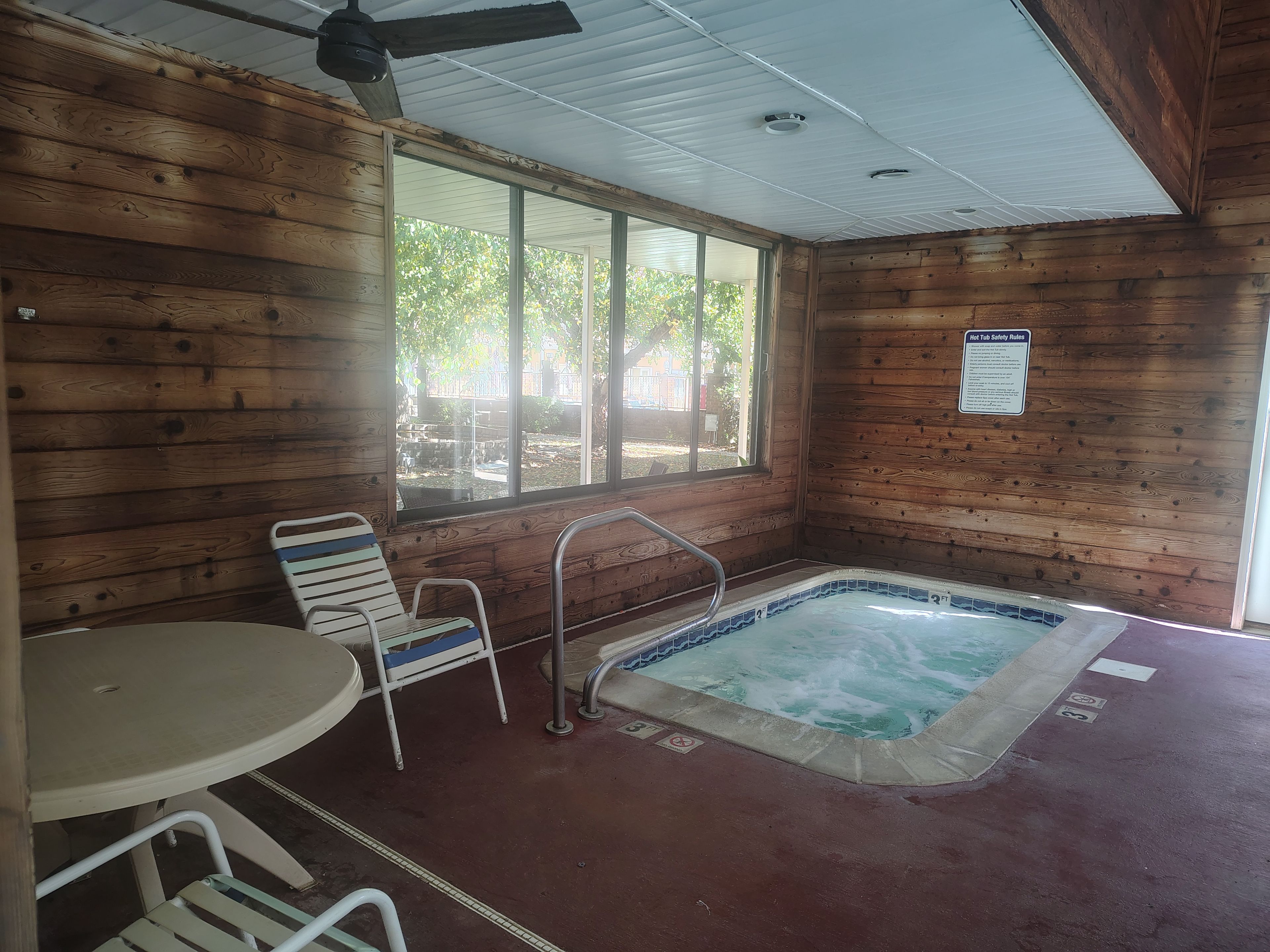 A hot tub with a wooden interior, a window, and a table with chairs.