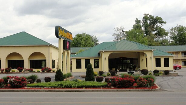 A motel with a green roof, a signboard, and a parking lot.