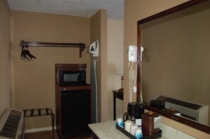 A bathroom with a hairdryer, a microwave, a small cabinet, and a mirror. - Golden Manor Inn & Suites (Muldraugh)