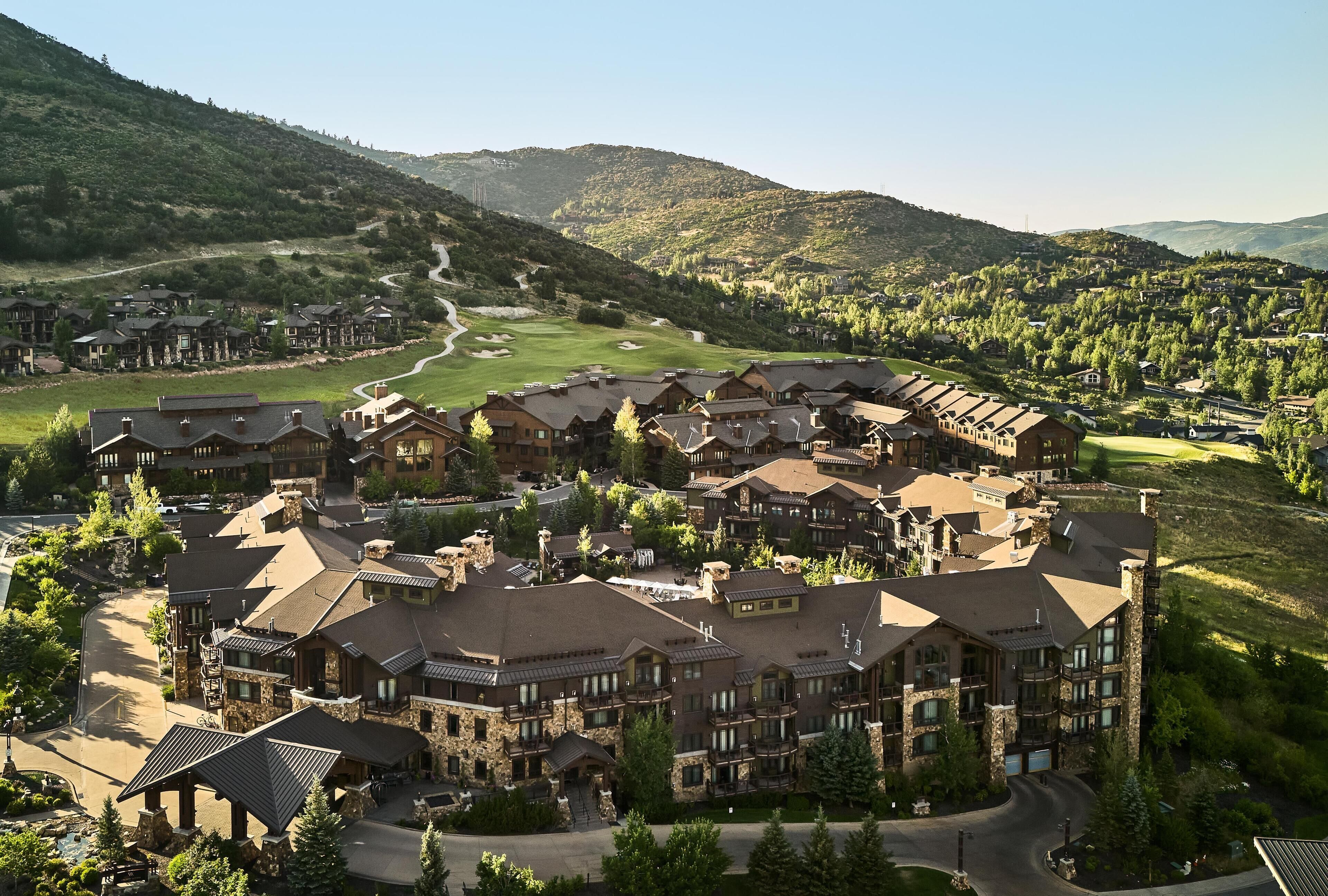 A resort with multiple buildings, a golf course, and a mountainous backdrop.