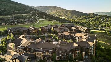 A resort with multiple buildings, a golf course, and a mountainous backdrop.