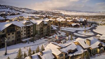 A snow-covered resort with multiple buildings, a ski lift, and a winding road.