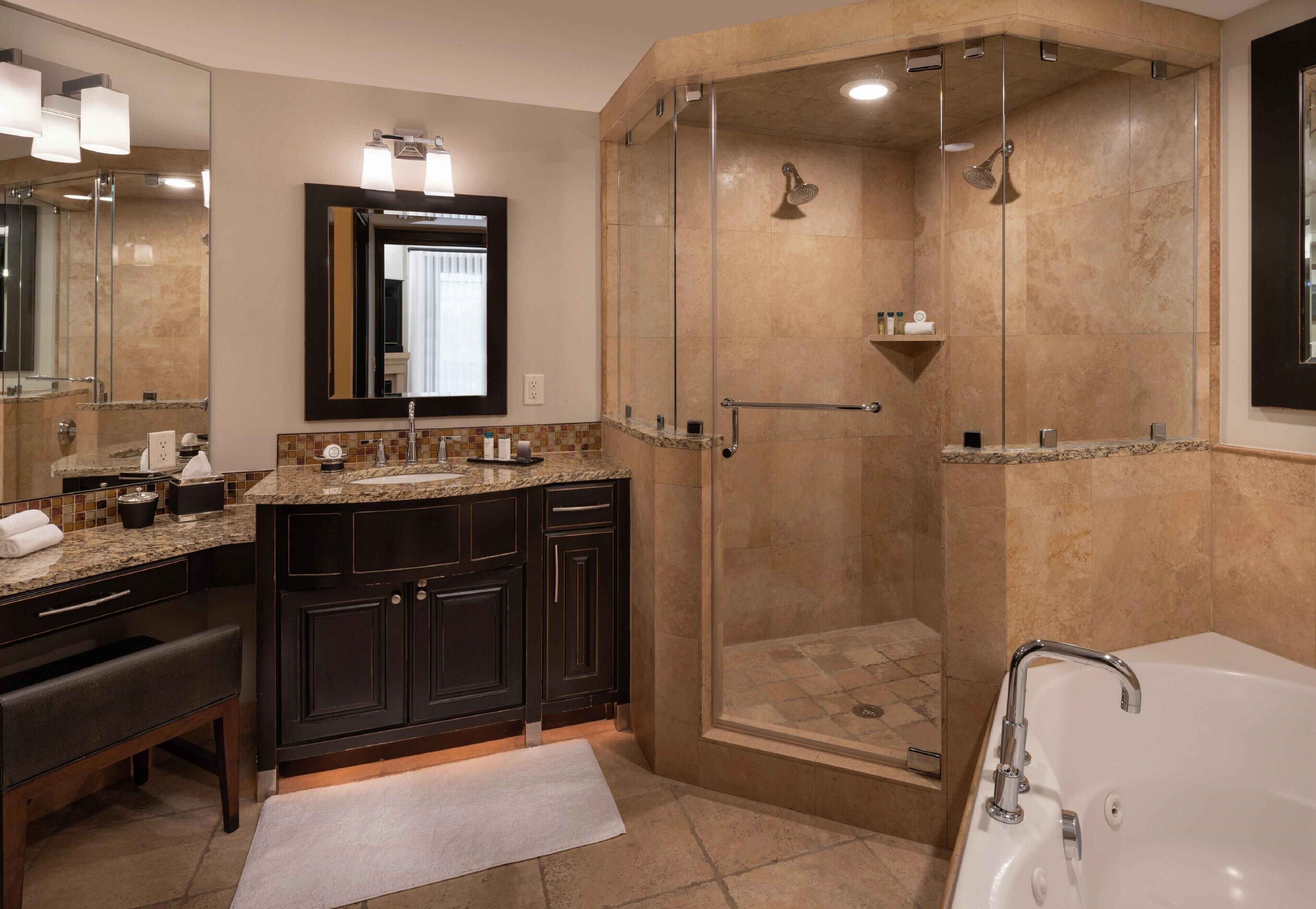 A modern bathroom with a walk-in shower, a bathtub, and a vanity with dark cabinets and a granite countertop.