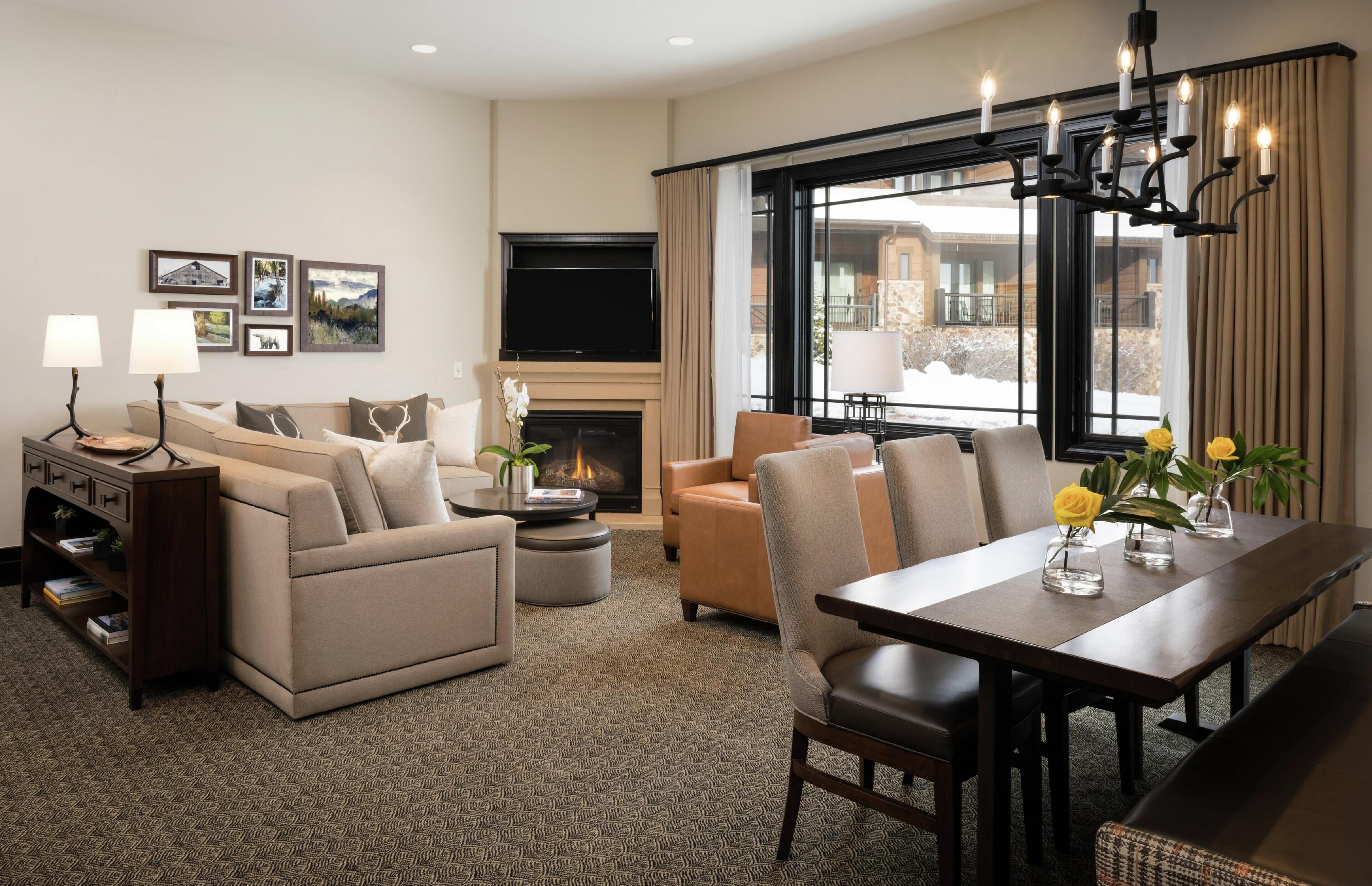 Ein modernes Hotelzimmer mit Kamin, Essbereich und Sitzecke mit Sofas und Couchtisch.