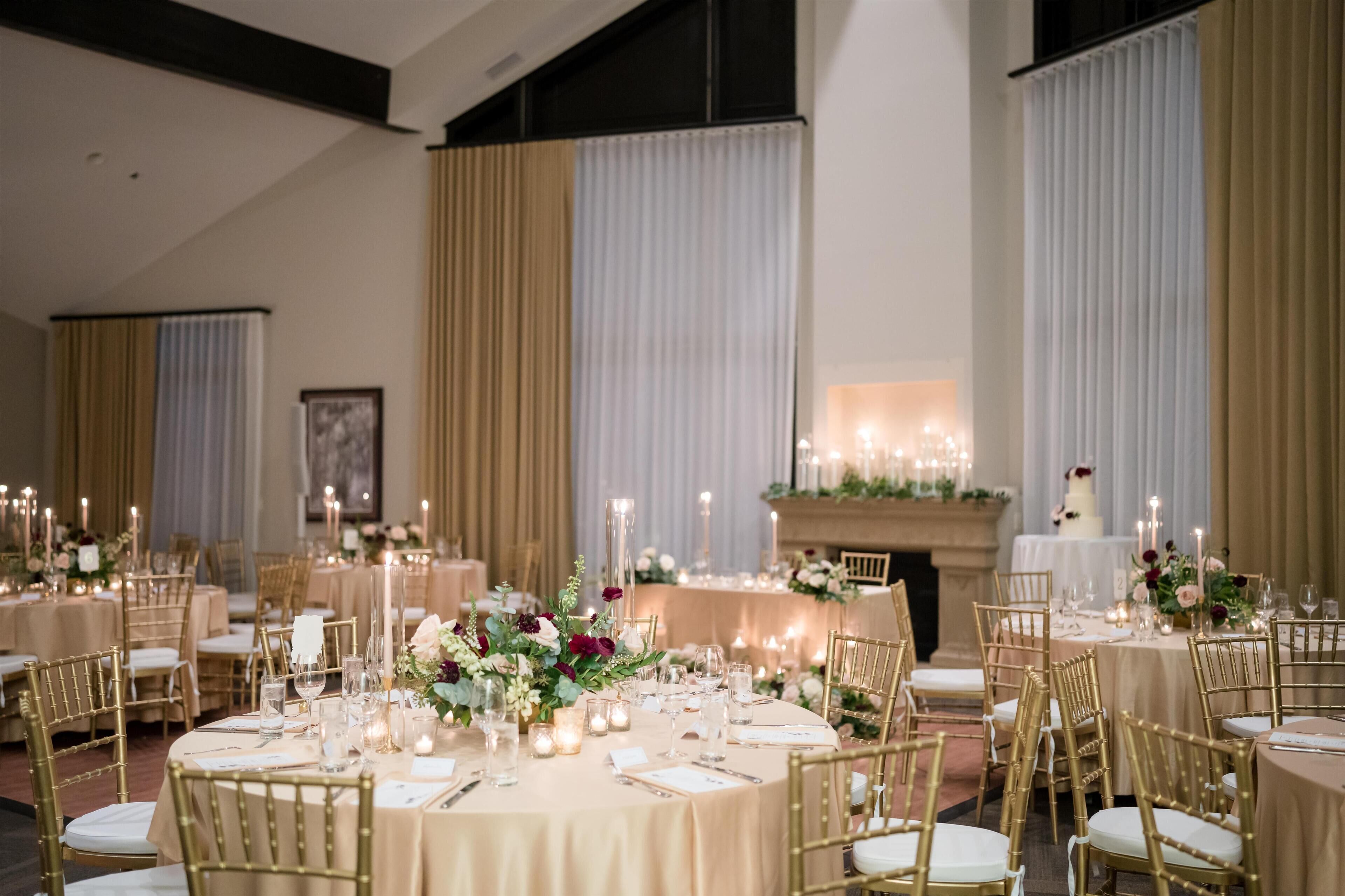 Une salle de banquet avec des tables rondes, des chaises dorées et des centres de table floraux.