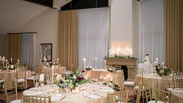 Une salle de banquet avec des tables rondes, des chaises dorées et des centres de table floraux.