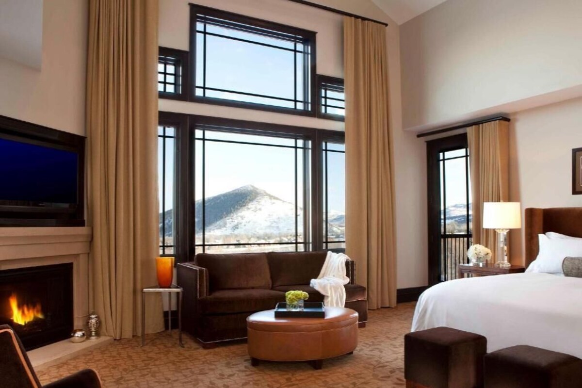 Ein Hotelzimmer mit Kamin, einem großen Bett, einer Couch, einem Couchtisch und einem Fernseher.