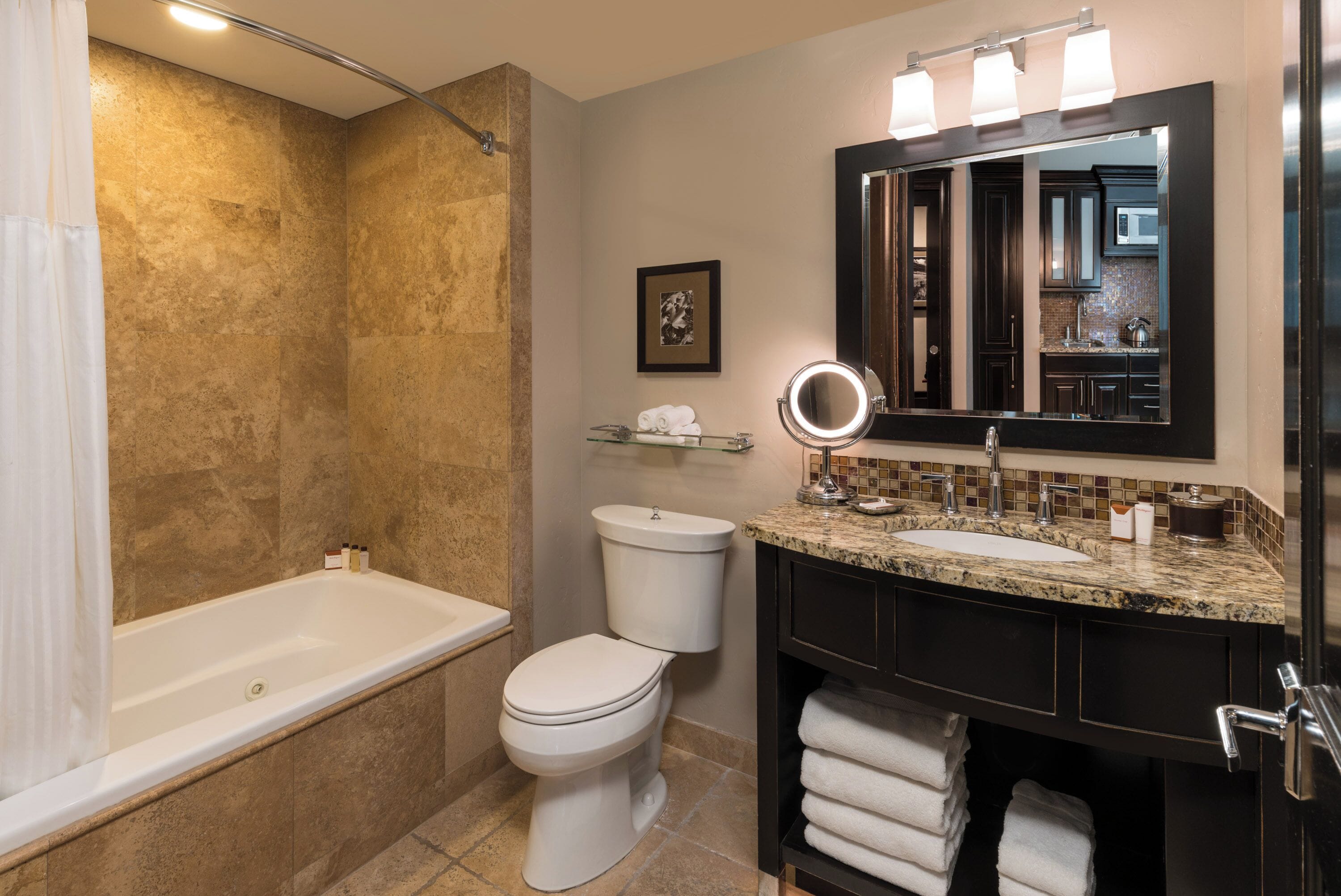 A modern bathroom with a bathtub, toilet, and vanity with a sink and mirror.