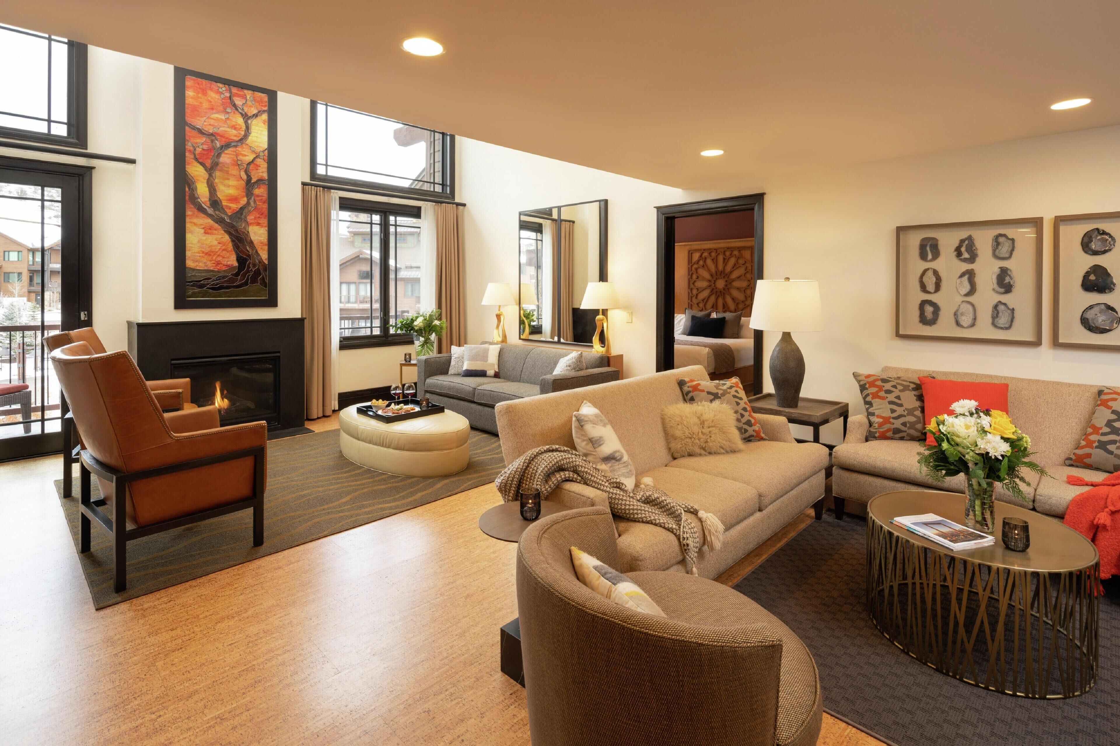 A spacious living room with a fireplace, comfortable seating, and large windows offering a view of the outside.