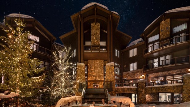 A multi-story building with a stone facade, balconies, and a central fireplace. - Waldorf Astoria Park City (Park City)