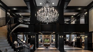 A grand lobby with a large chandelier, a staircase, and a seating area with a coffee table. - Waldorf Astoria Park City (Park City)