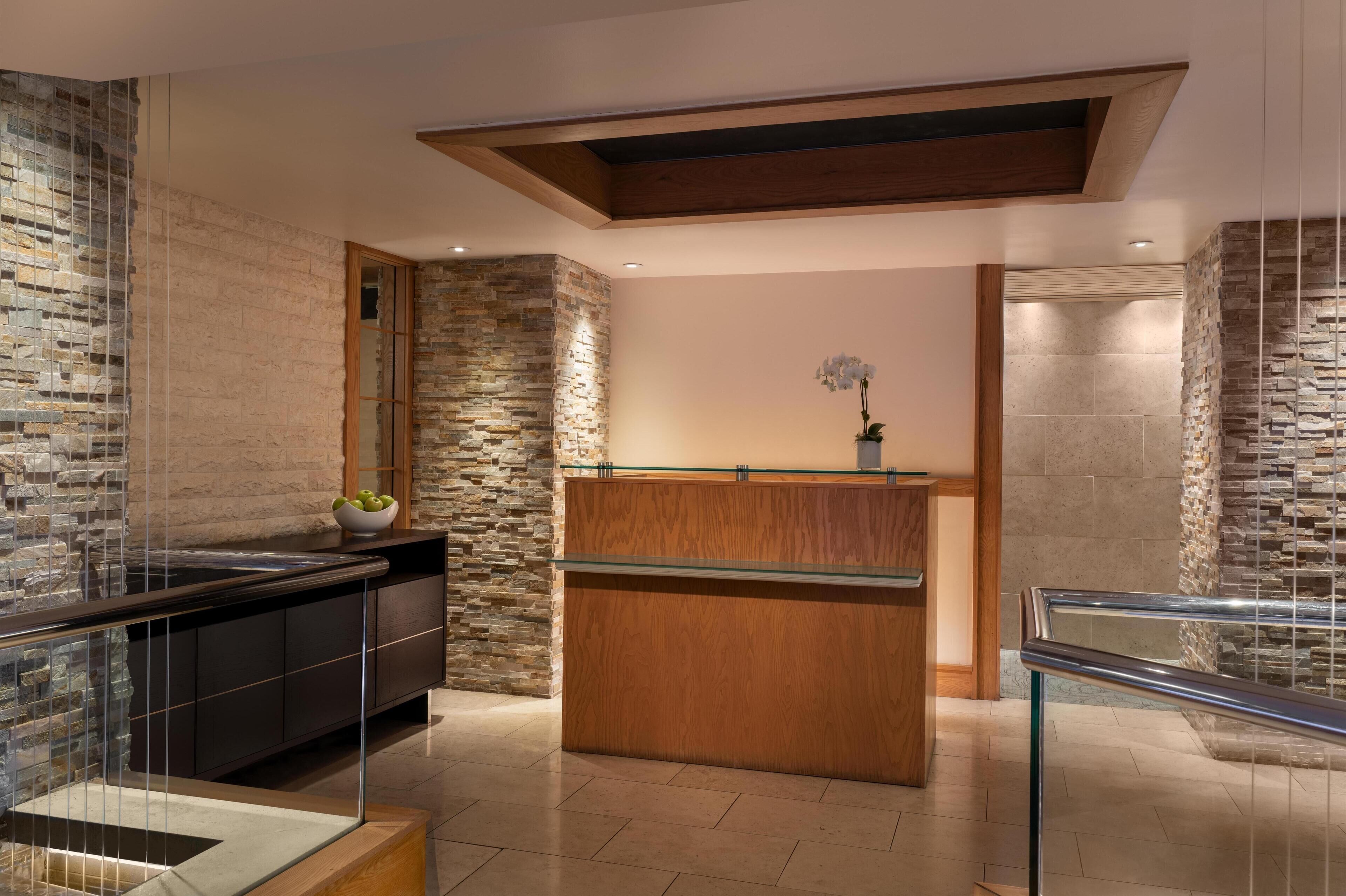 A modern kitchen with a stone backsplash, wooden counter, and glass railing.