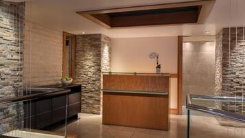 A modern kitchen with a stone backsplash, wooden counter, and glass railing.