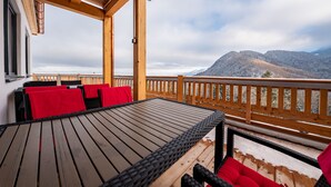 A wooden deck with a table and chairs, overlooking a mountainous landscape. - Berggasthof Hotel Adersberg (Grassau)