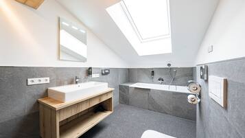 Een moderne badkamer met dakraam, een houten wastafelmeubel, een grote wastafel en een aparte douchecabine.
