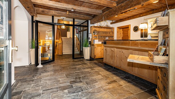 A wooden interior with a stone floor, wooden cabinets, and a staircase leading to another room. - Berggasthof Hotel Adersberg (Grassau)