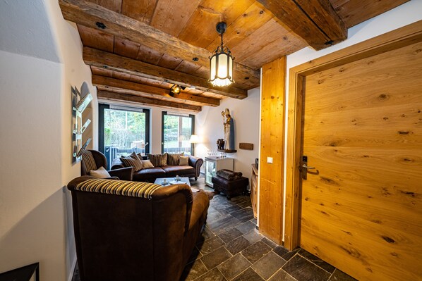 Ein gemütliches Wohnzimmer mit einem braunen Ledersofa, einem kleinen Tisch und einer Holztür.