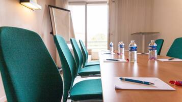 A conference room with green chairs, a long table, water bottles, and a whiteboard.