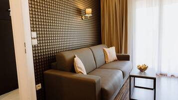 A modern living room with a patterned wall, a sofa, a side table, and a lamp.