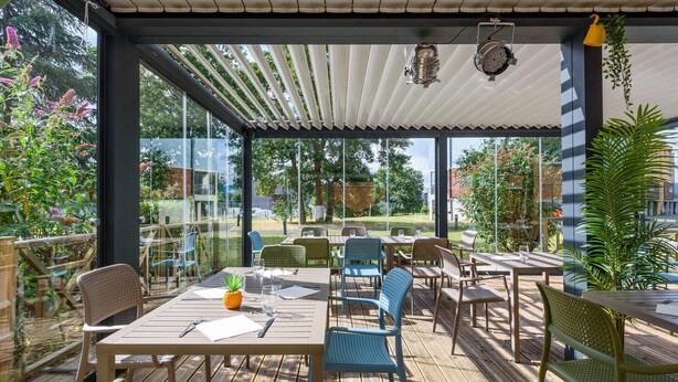 Une terrasse extérieure avec des tables et des chaises en bois, une pergola et des plantes en pot.