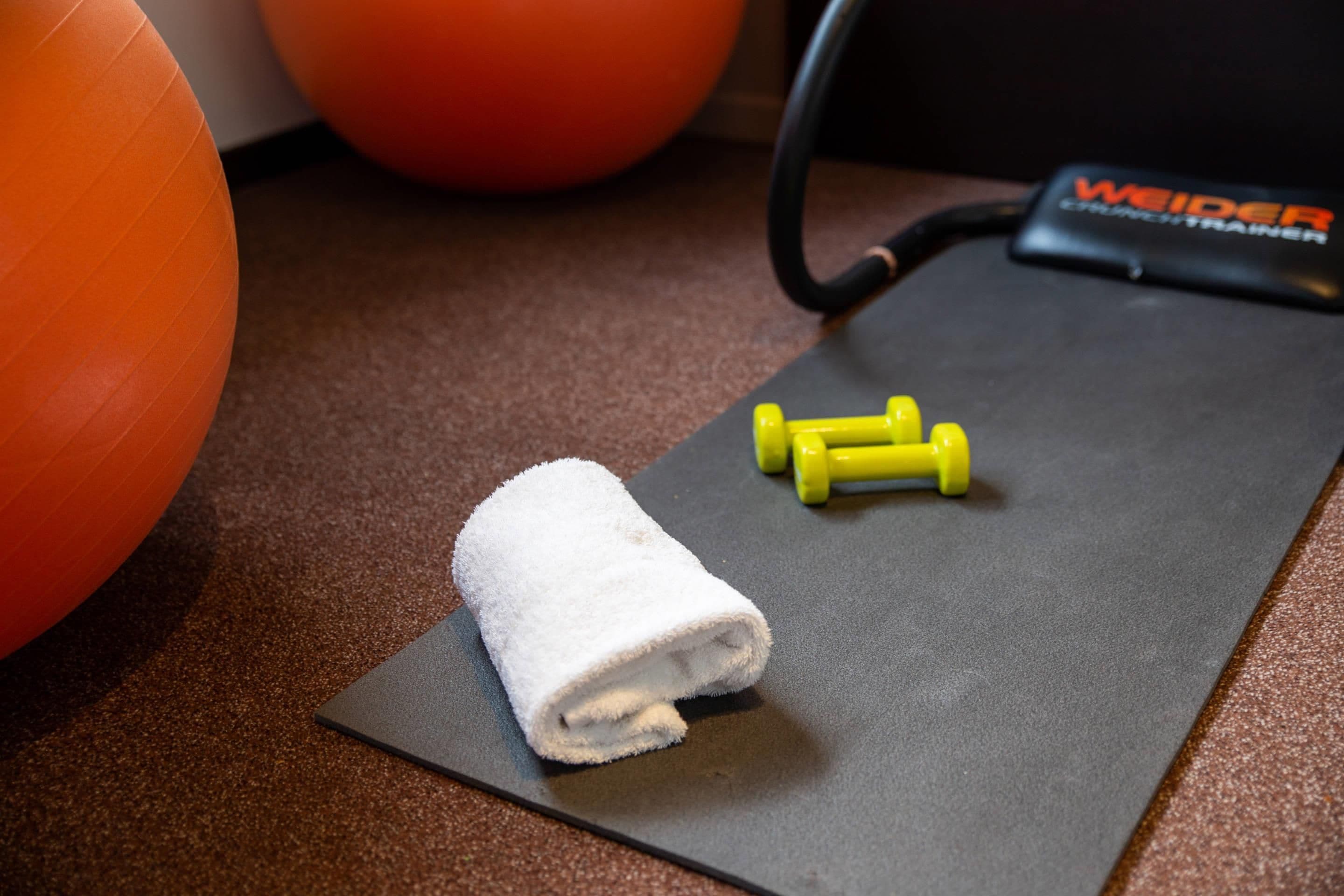 A gym setting with exercise equipment, including a yoga mat, dumbbells, and a resistance band.