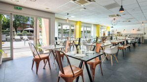 Un restaurant moderne, doté d’un intérieur lumineux, de grandes fenêtres et de différents types de sièges.