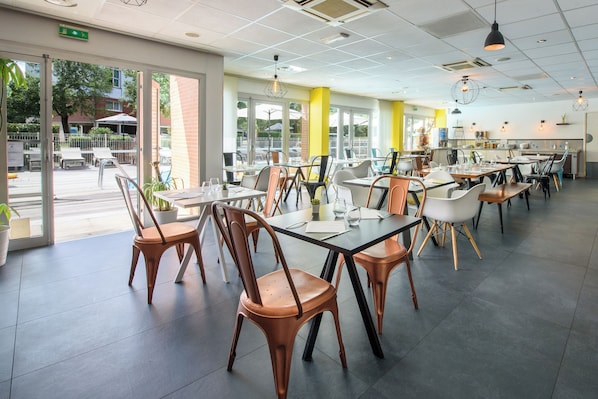 A modern restaurant with a bright interior, large windows, and a variety of seating options.