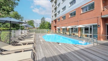 Una piscina al aire libre, sillones reclinables de piscina