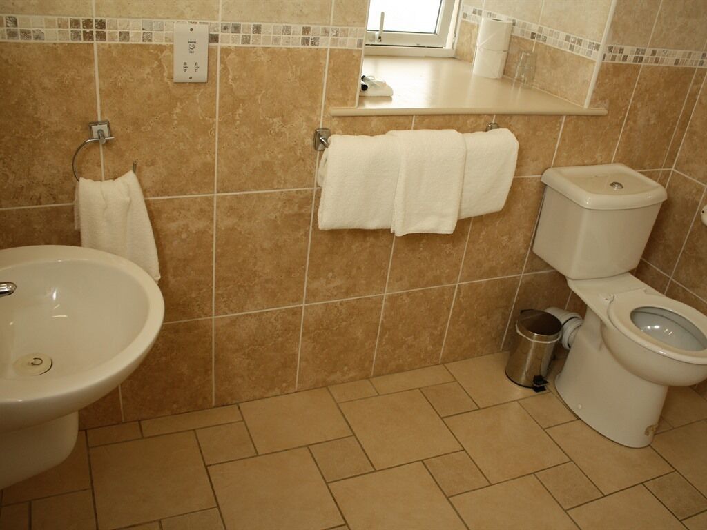 Une salle de bain avec un lavabo, des toilettes et un miroir au-dessus du lavabo.