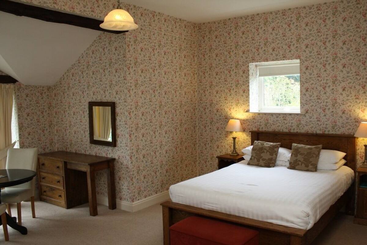 Ein Schlafzimmer mit einem Bett, Nachttischen, einem Schreibtisch und einem Sessel.