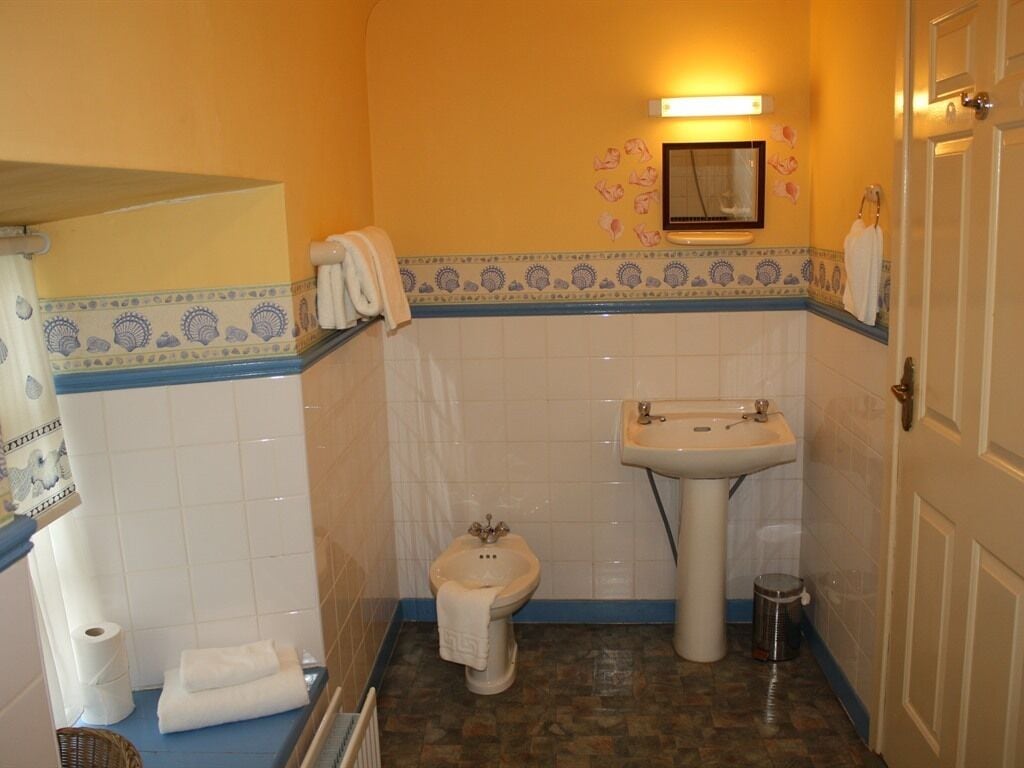 Un baño con inodoro, lavabo y un perchero para toallas.