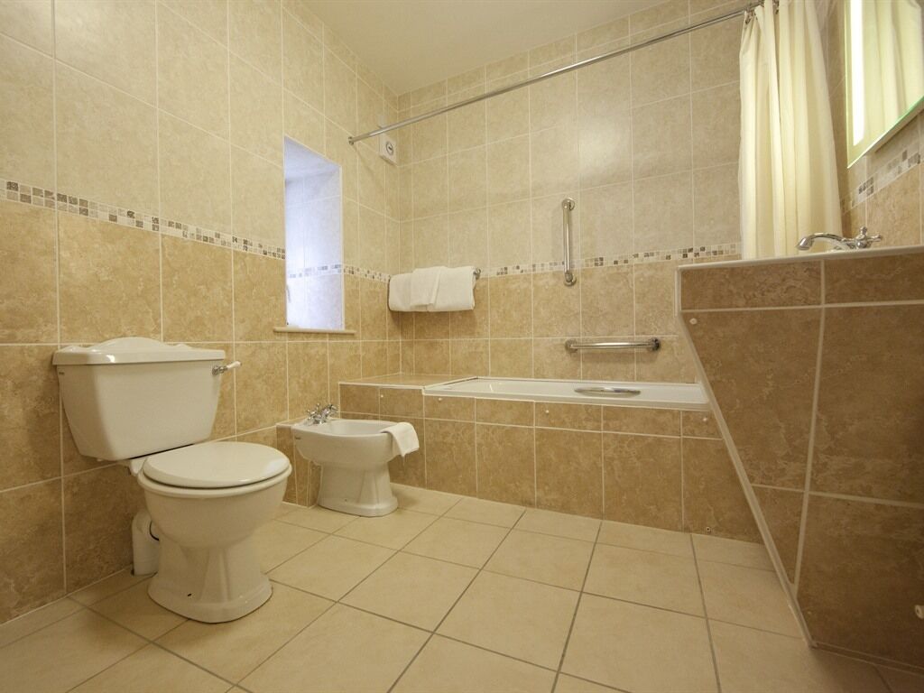 A bathroom with a toilet, bidet, and bathtub.