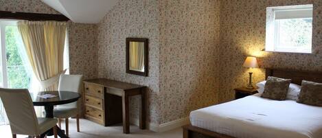 A bedroom with a bed, a desk, a chair, a lamp, and a window.